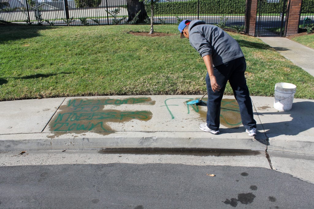A man using a paint mop with liquid graffiti remover to remove spray paint from concrete.