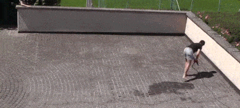 A man cleans a brick surface with a pressure washer.