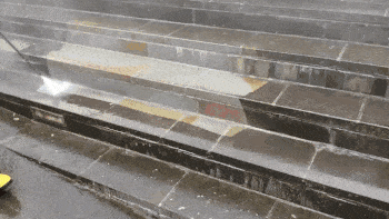 A worker cleans slate stairs with a power washer. 