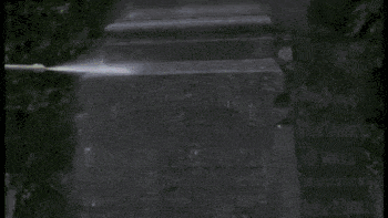 A gravestone is cleaned using a power washer.