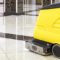 Yellow floor cleaning machine on shiny marble tiles in a building lobby.