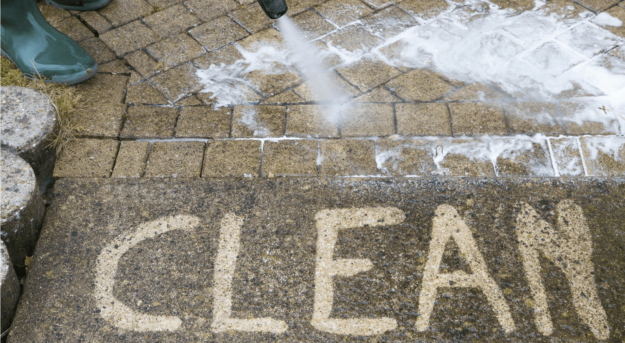 Clean concrete with pressure washer A person pressure washing a patio with the word "CLEAN" appearing on the surface.