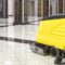 A floor cleaning machine in a shiny, marble-floored lobby with elevators in the background.