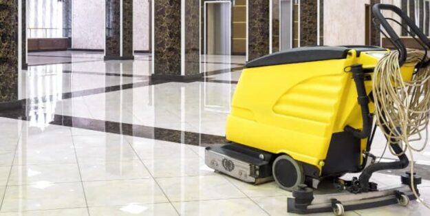 floor scrubbers & linoleum A floor cleaning machine in a shiny, marble-floored lobby with elevators in the background.