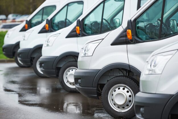 The Role of Pressure Washing in Commercial Fleet Management Row of white commercial vans lined up in wet parking lot.