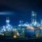 Industrial plant at night with illuminated towers and large spherical storage tanks against a dark sky.