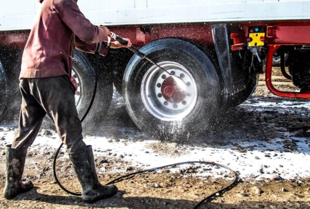 Best Practices for Pressure Washing in Cold Weather Man pressure washing truck tires outside.
